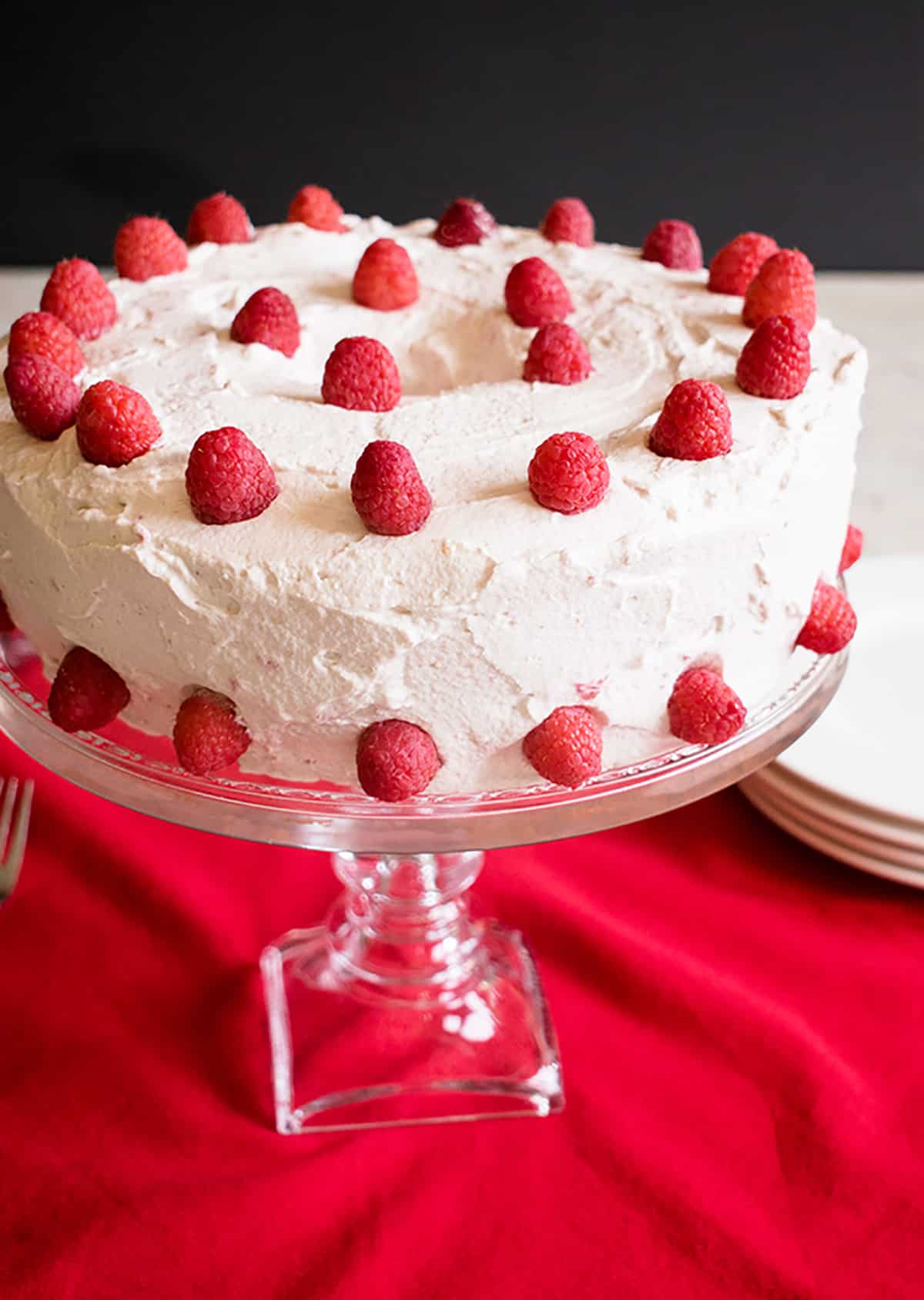 cake with whipped cream and raspberries on a cake stand