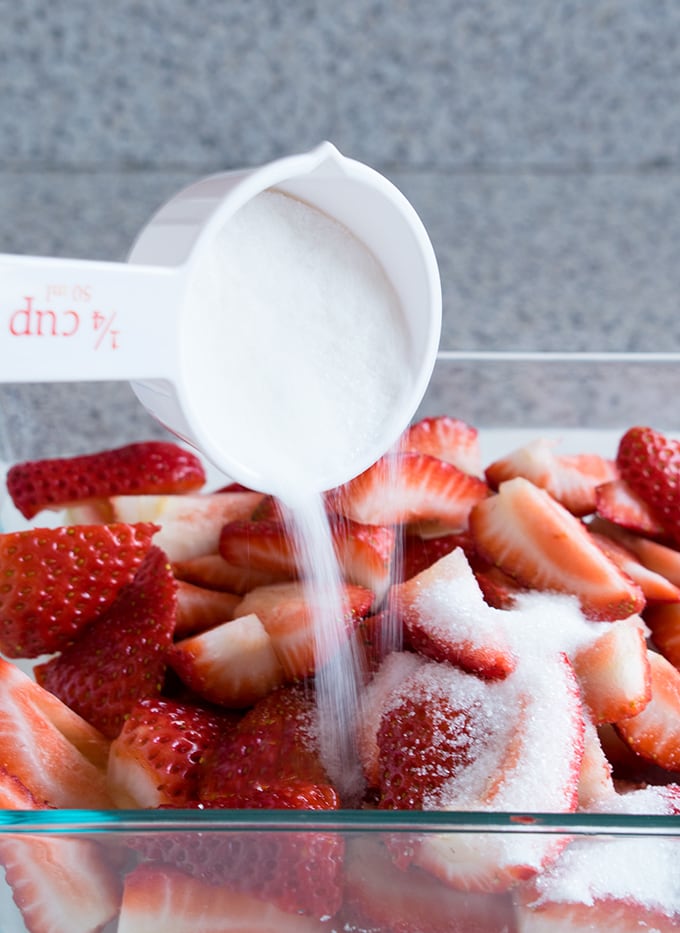 sugar being poured onto strawberries