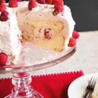cake stand holding Raspberry-Almond Angel Food Cake with a wedge removed