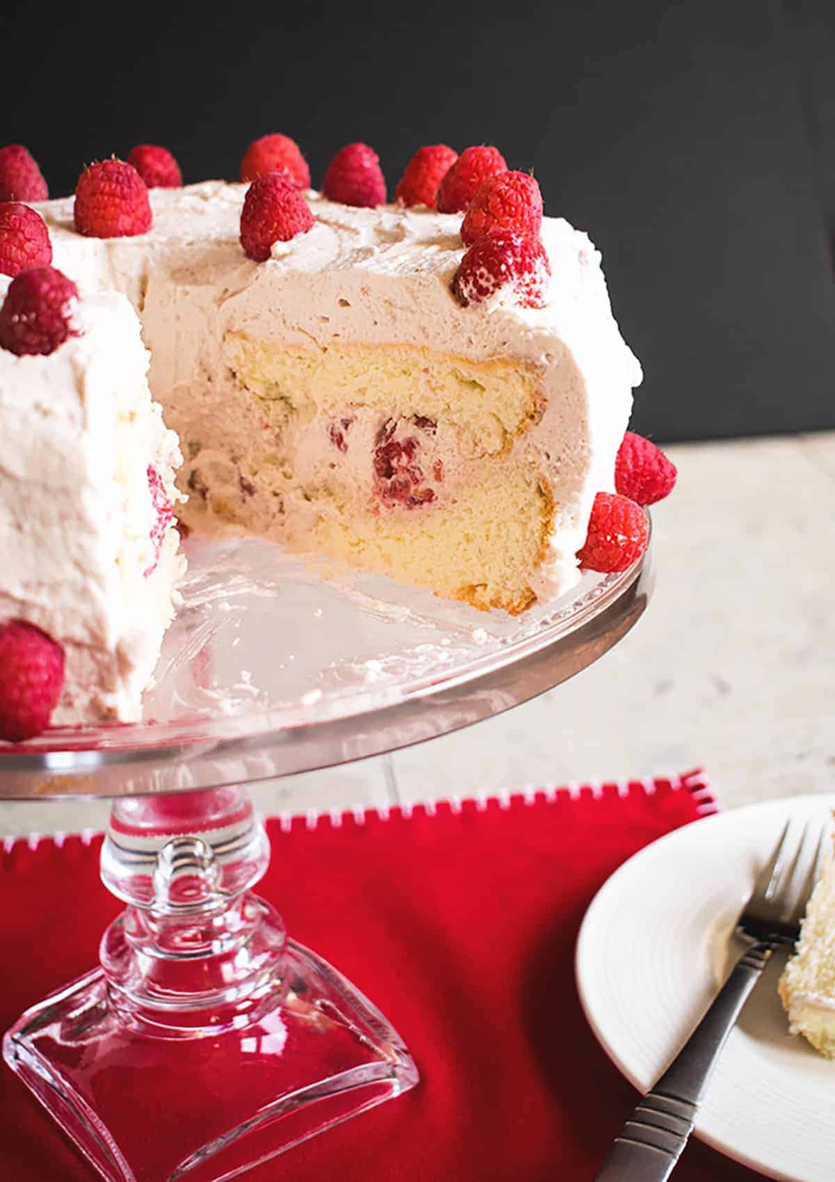 cake stand holding Raspberry-Almond Angel Food Cake with a wedge removed