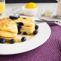 stack of lemon-blueberry pancakes with a wedge removed