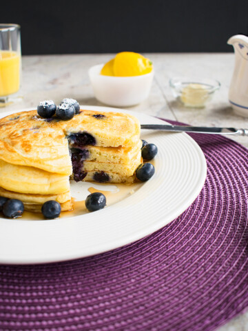 stack of lemon-blueberry pancakes with a wedge removed