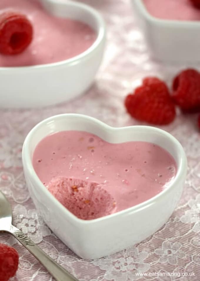 raspberry yogurt mousse pot in a heart-shaped bowl, bite has been taken out 