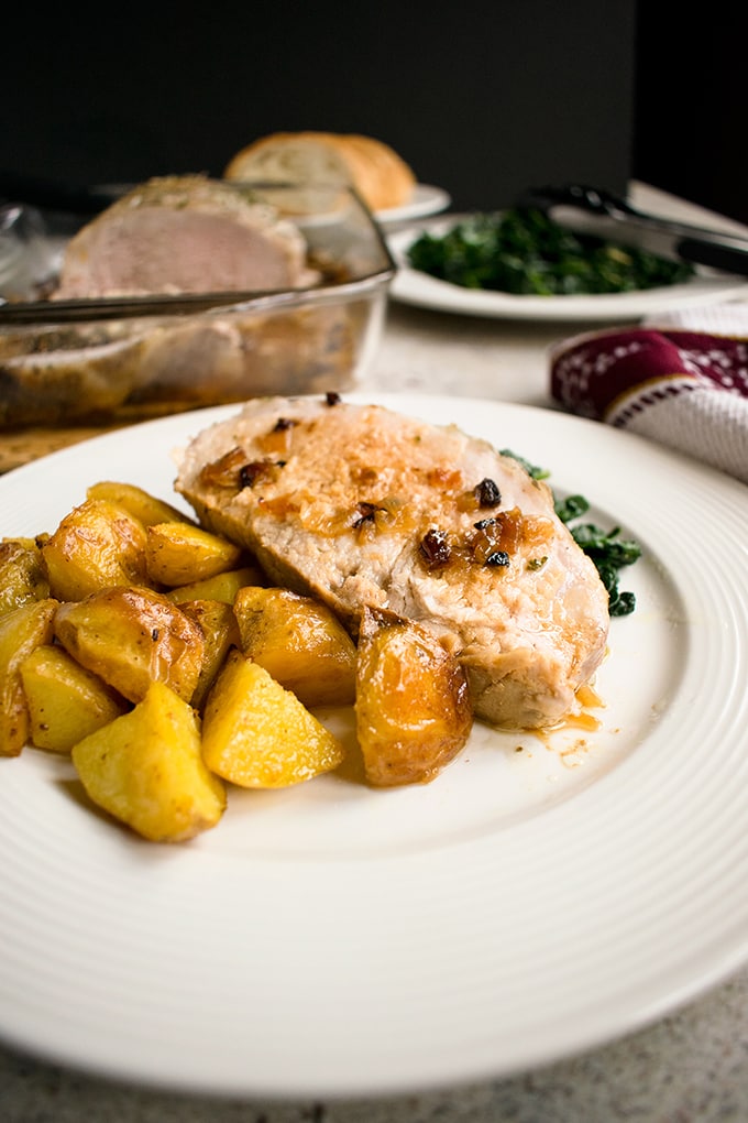 slice of Roasted Pork Loin with Rosemary and Garlic on a plate with cooked potatoes