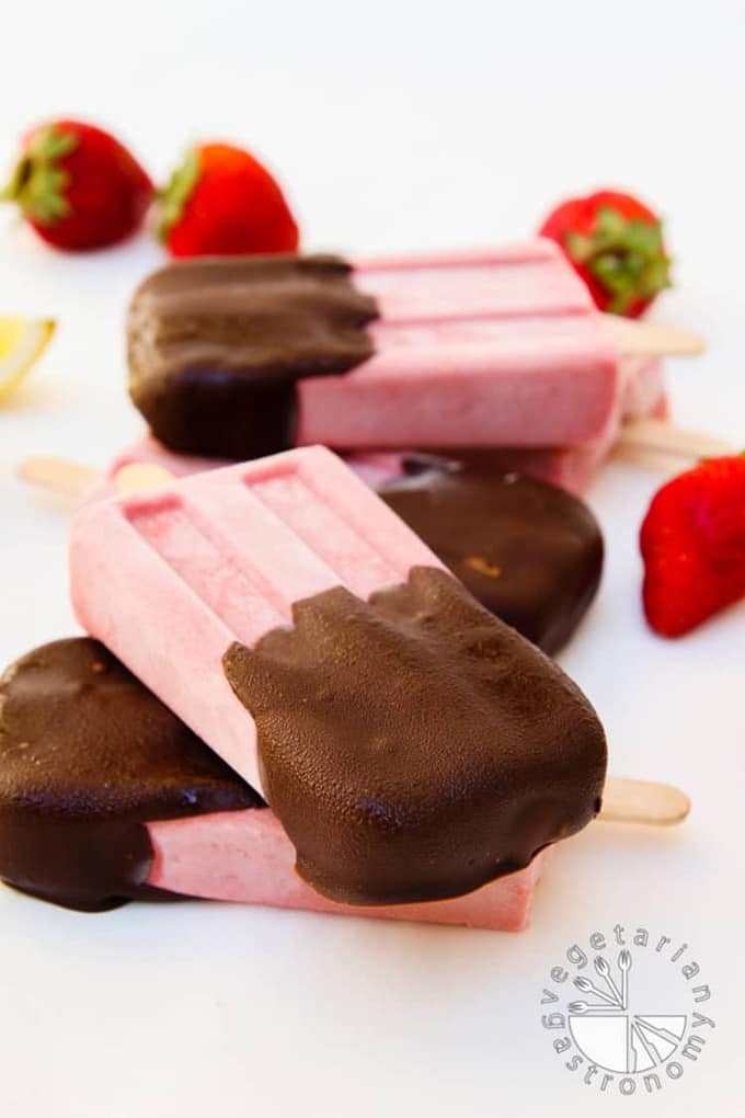 chocolate covered strawberry cream popsicles stacked on top of each other