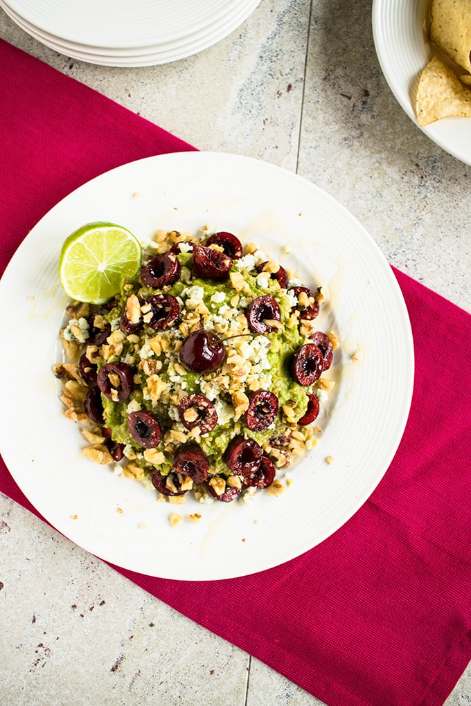 overhead shot of guacamole with cherries, gorgonzola and walnuts in a bowl