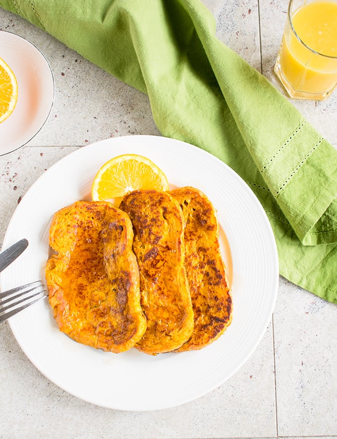 overhead view of pumpkin-orange french toast on a plate with fork and knife