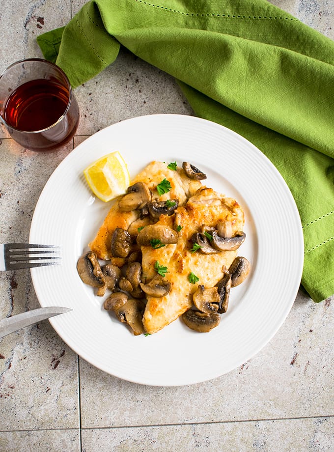 overhead view of chicken marsala with mushrooms on a plate with fork and knife