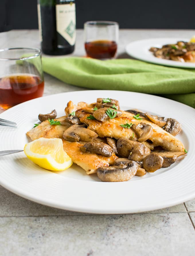 side view of chicken marsala with mushrooms on a plate 