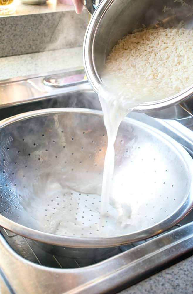 pot of cooked long-grain rice being poured into a colander 