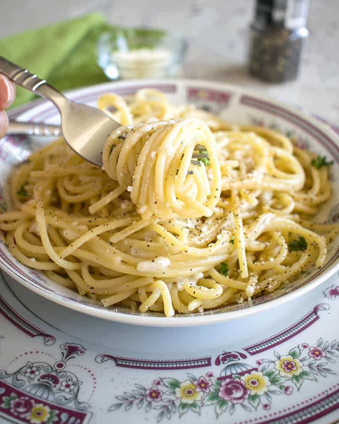 forkful of pasta with pecorino being taken from a bowl