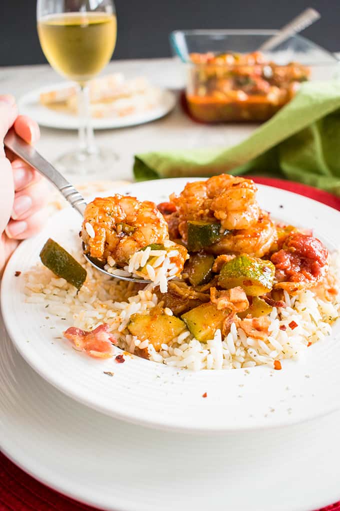 shrimp stew with bacon over rice in a bowl with forkful being pulled out