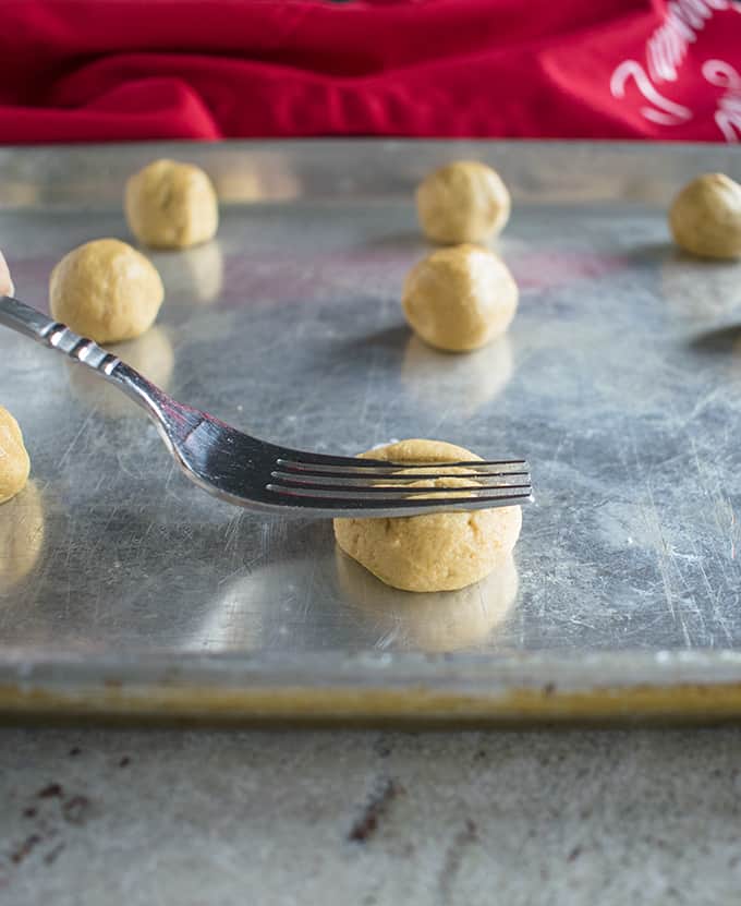peanut butter cookie dough on a sheet pan with a fork pressing down to give texture