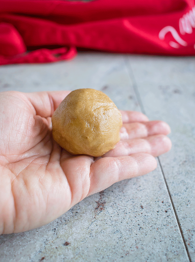hand holding a ball of peanut butter cookie dough
