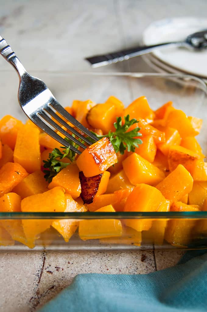 roasted butternut squash cubes in a glass container with a fork