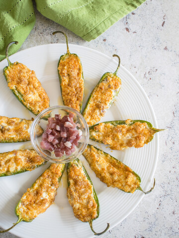 overhead photo of baked parmesan jalapeno poppers with prosciutto on a plate