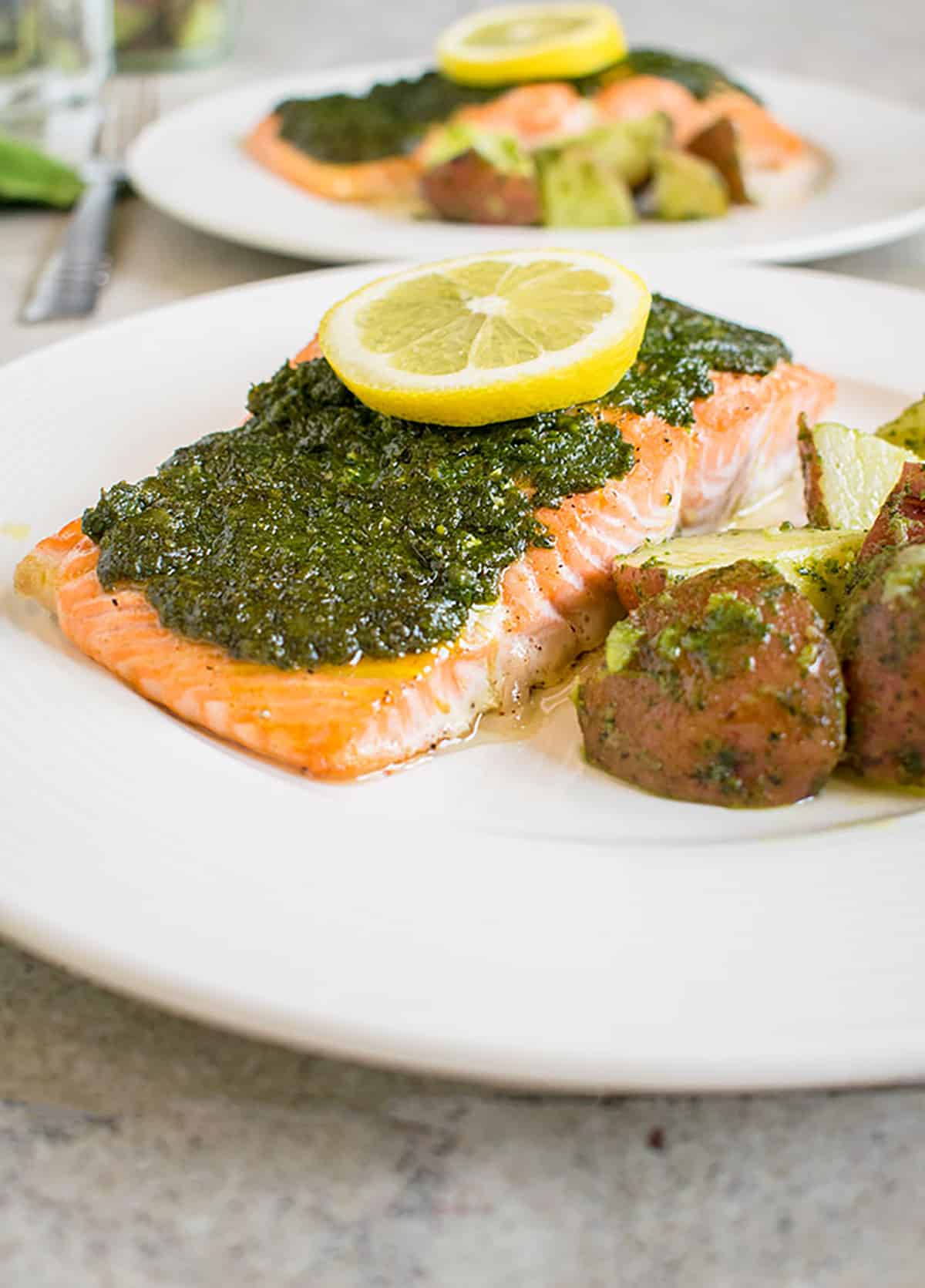 plate of pesto salmon with a slice of lemon, redskin potatoes on side