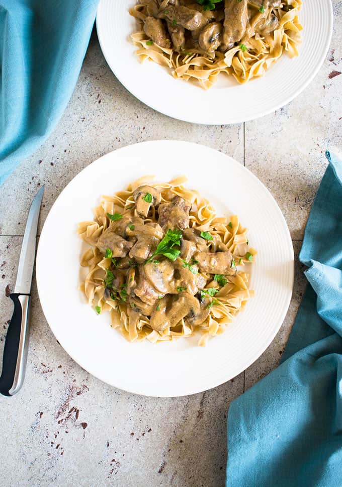 overhead photo of 2 plates of tender beef stroganoff with napkins 