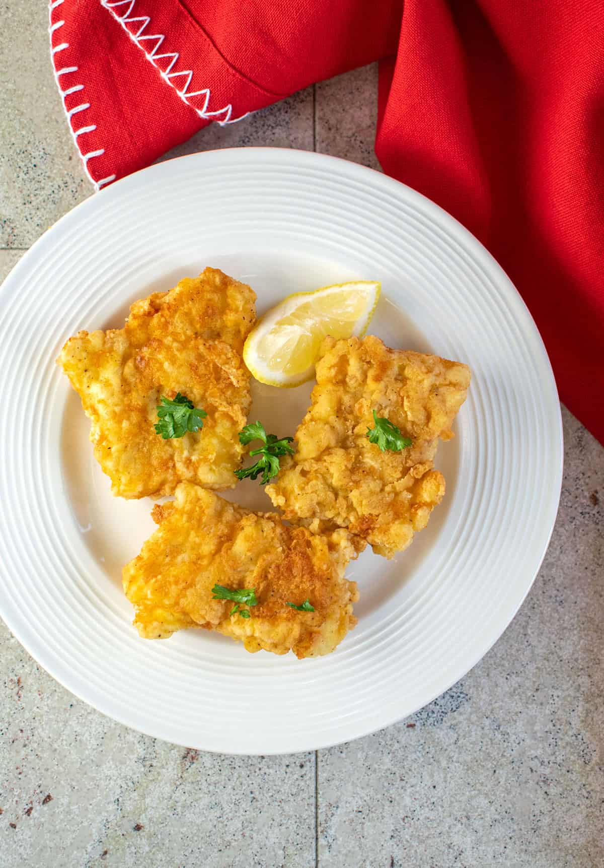 overhead photo of fried baccala (salted cod fish) with lemon wedge 