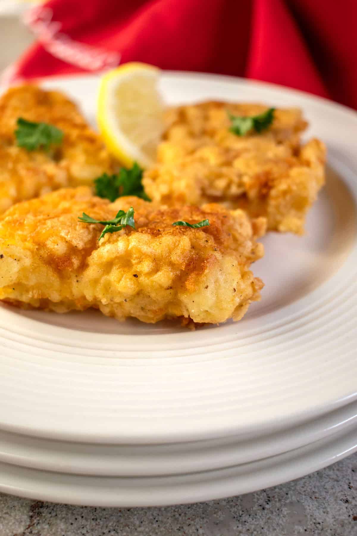 Fried Baccala (salted cod fish) on a plate with a lemon wedge on a plate