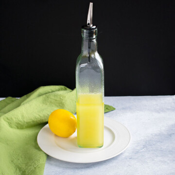 bottle of lemon olive oil on plate with a lemon and green napkin