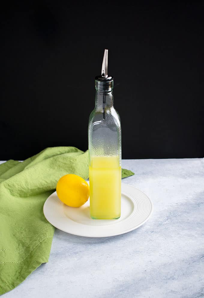 bottle of lemon olive oil on plate with a lemon and green napkin