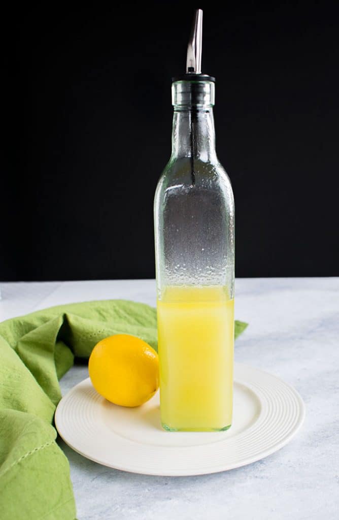 bottle of lemon olive oil on plate with a lemon