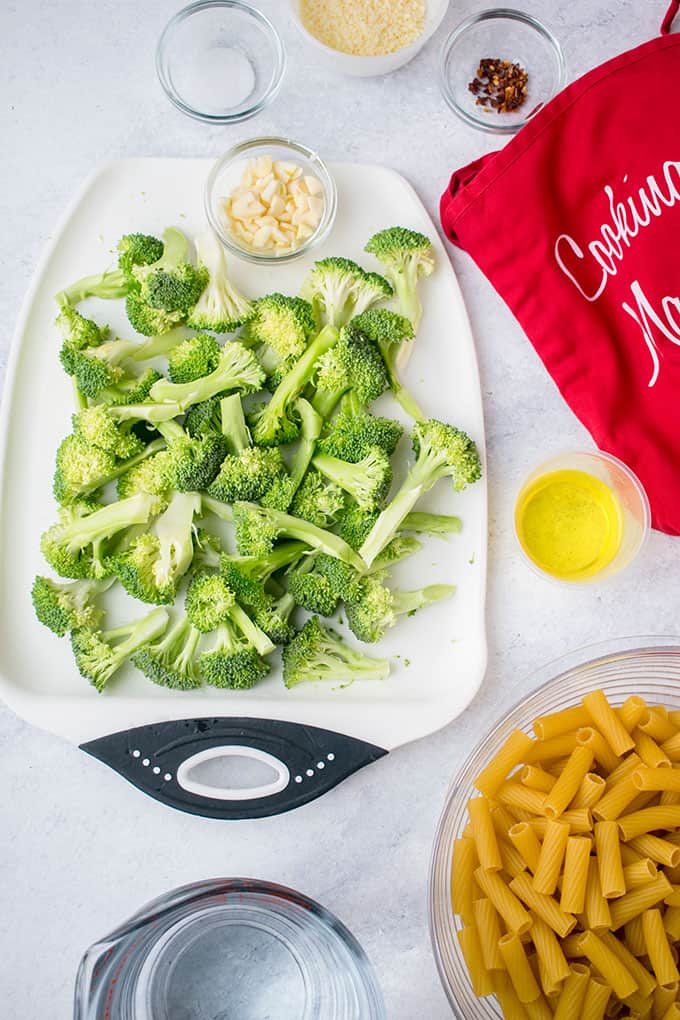Overhead view of the ingredients for pasta with broccoli ingredients: Pasta, broccoli, olive oil, garlic, red pepper flakes, salt, water and parmesan cheese
