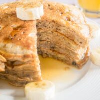 stack of banana pancakes on a plate with banana slices