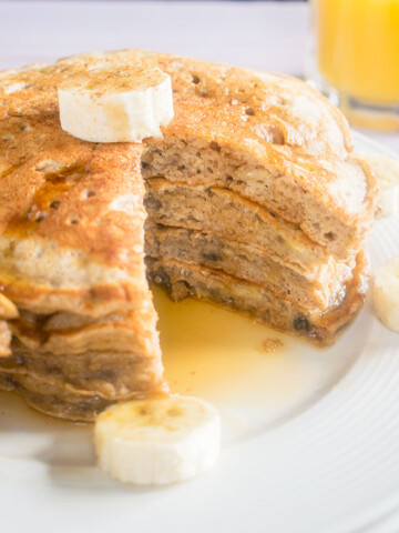 stack of banana pancakes on a plate with banana slices