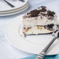 Slice of Oreo Ice Cream Cake on white plate with a spoon