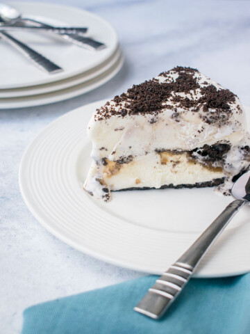Slice of Oreo Ice Cream Cake on white plate with a spoon