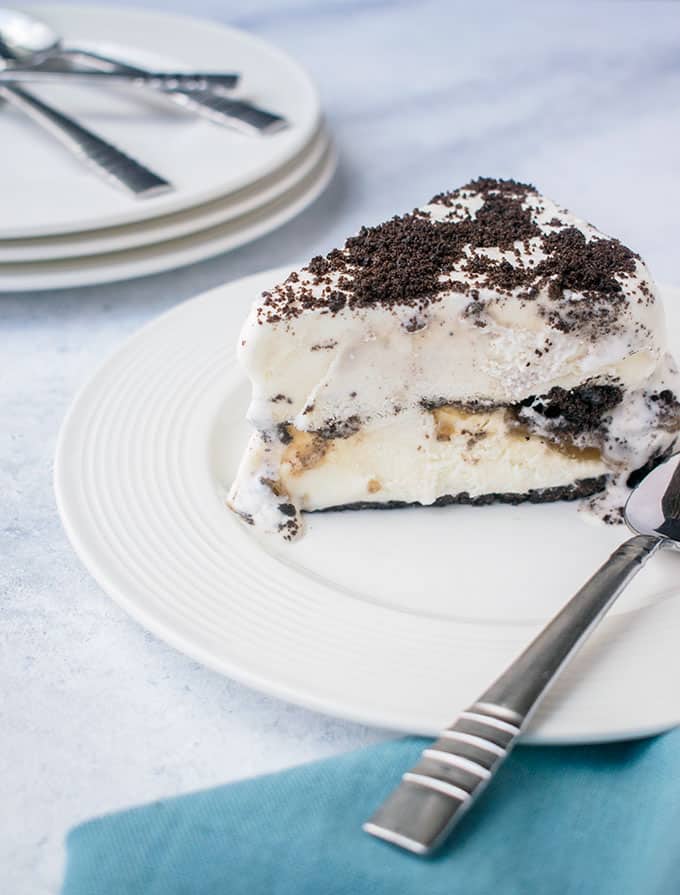 Slice of Oreo Ice Cream Cake on white plate with a spoon