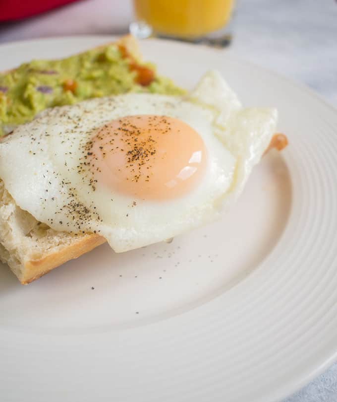 Side view of a basted egg with guacamole on toast 
