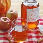mason jar and glass mug of apple pie moonshine, apples