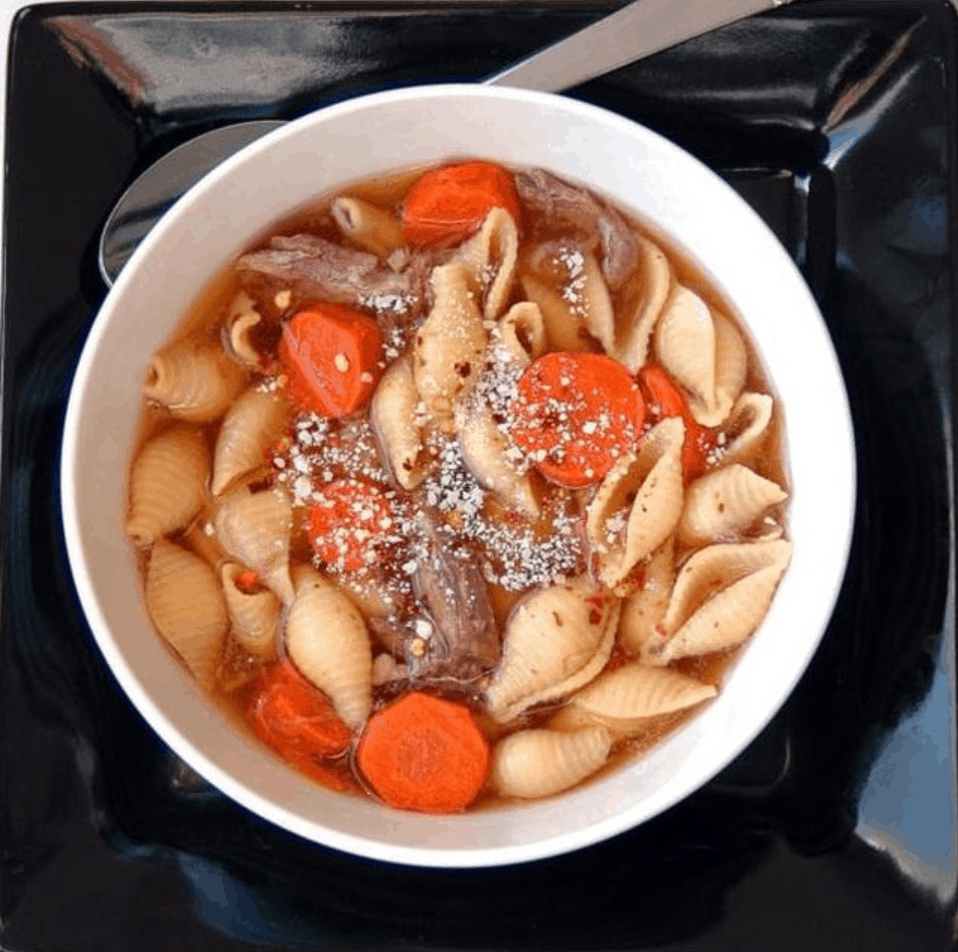 bowl of soup with pasta shells, beef, carrots