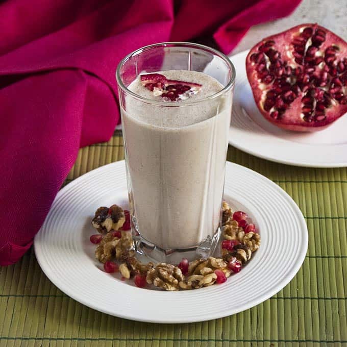 smoothie in a tall glass with walnuts and pomegranate