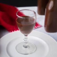 glass of chocolate liqueur on white plate with red napkin