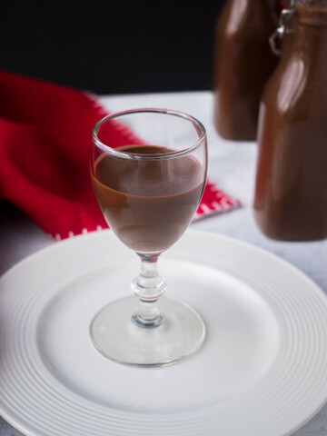 glass of chocolate liqueur on white plate with red napkin
