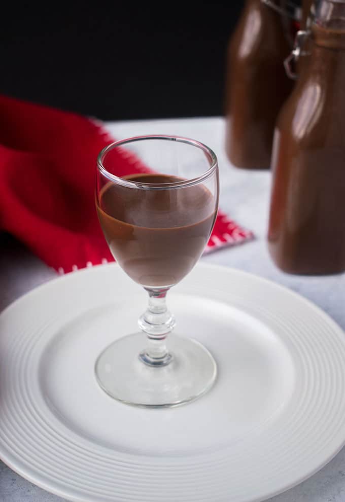 glass of chocolate liqueur on white plate with red napkin