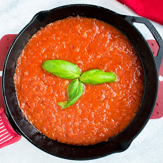 overhead view of sauce in pan with basil