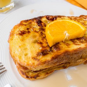 stack of French Toast with syrup and orange slice