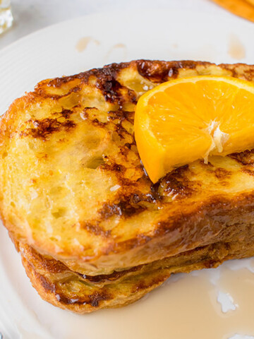 stack of French Toast with syrup and orange slice