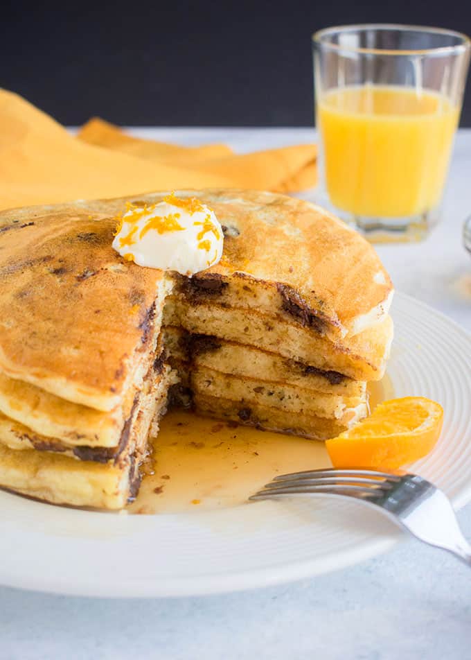 cut open stack of chocolate chip pancakes with butter and orange zest on top