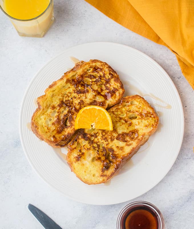 plate of French Toast with syrup and orange slice