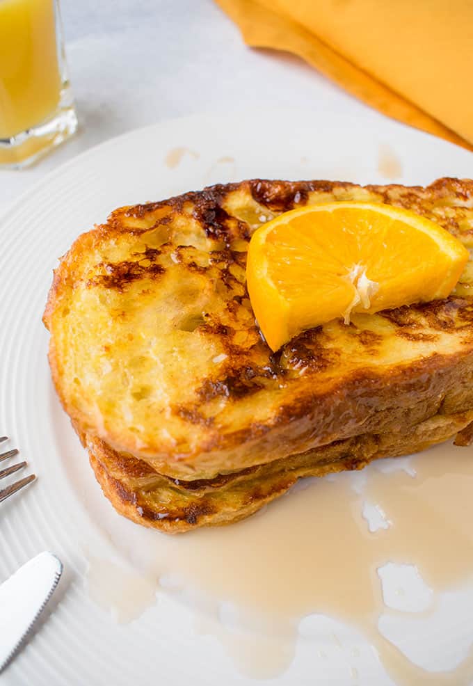 stack of French Toast with syrup and orange slice
