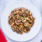 sliced cooked mushrooms on white plate, red napkin