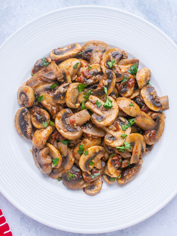 sliced cooked mushrooms on white plate, red napkin
