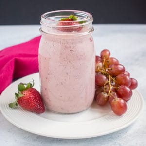 pink smoothie in jar, strawberries, grapes, pink napkin, white dish