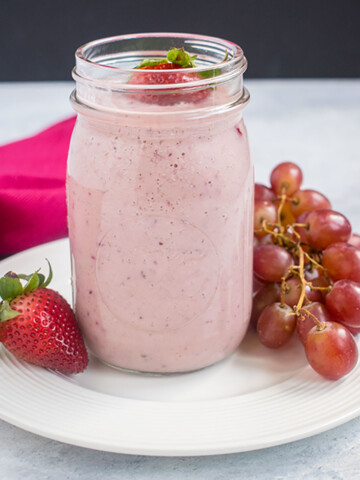 pink smoothie in jar, strawberries, grapes, pink napkin, white dish